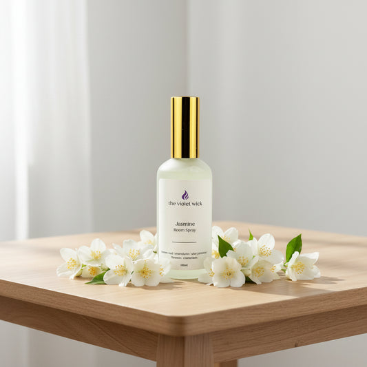 white room spray bottle labeled Jasmine on a coffee table with jasmine flowers