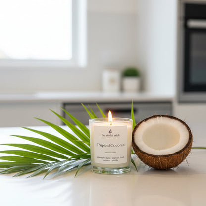 Tropical Coconut candle by The Violet Wick on a kitchen bench with palm leaf and coconut half.