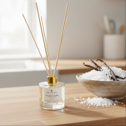 clear diffuser bottle with gold lid on timber bench with sea salt and vanilla