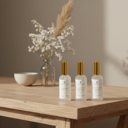 Three white room spray bottles on an entry table with vase of flowers